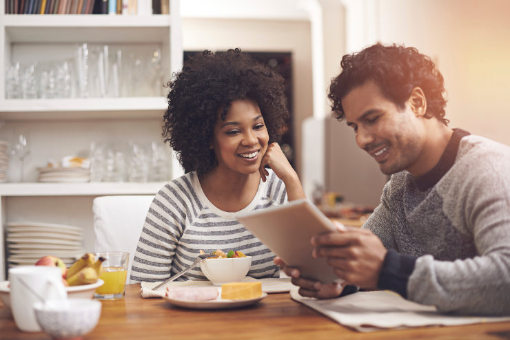 Smiling couple browsing for apartments on a tablet.